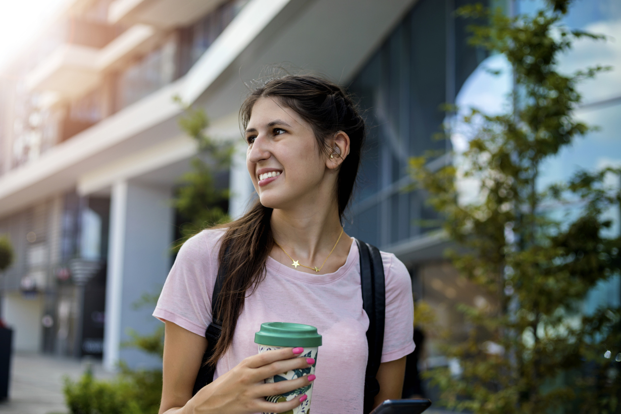 Teenage girl with hearing aid walking on city street