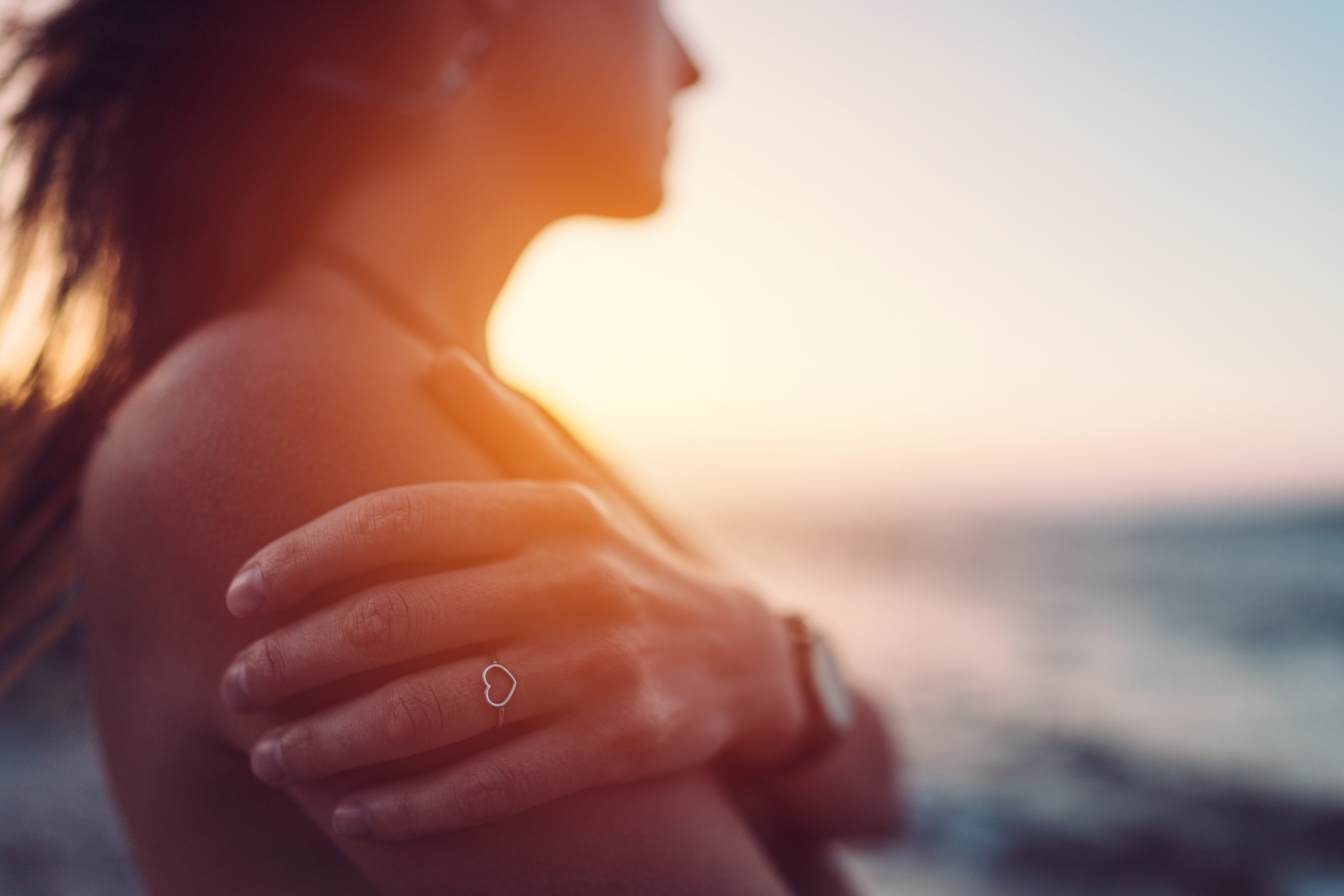 Woman at the seashore staring the sunset