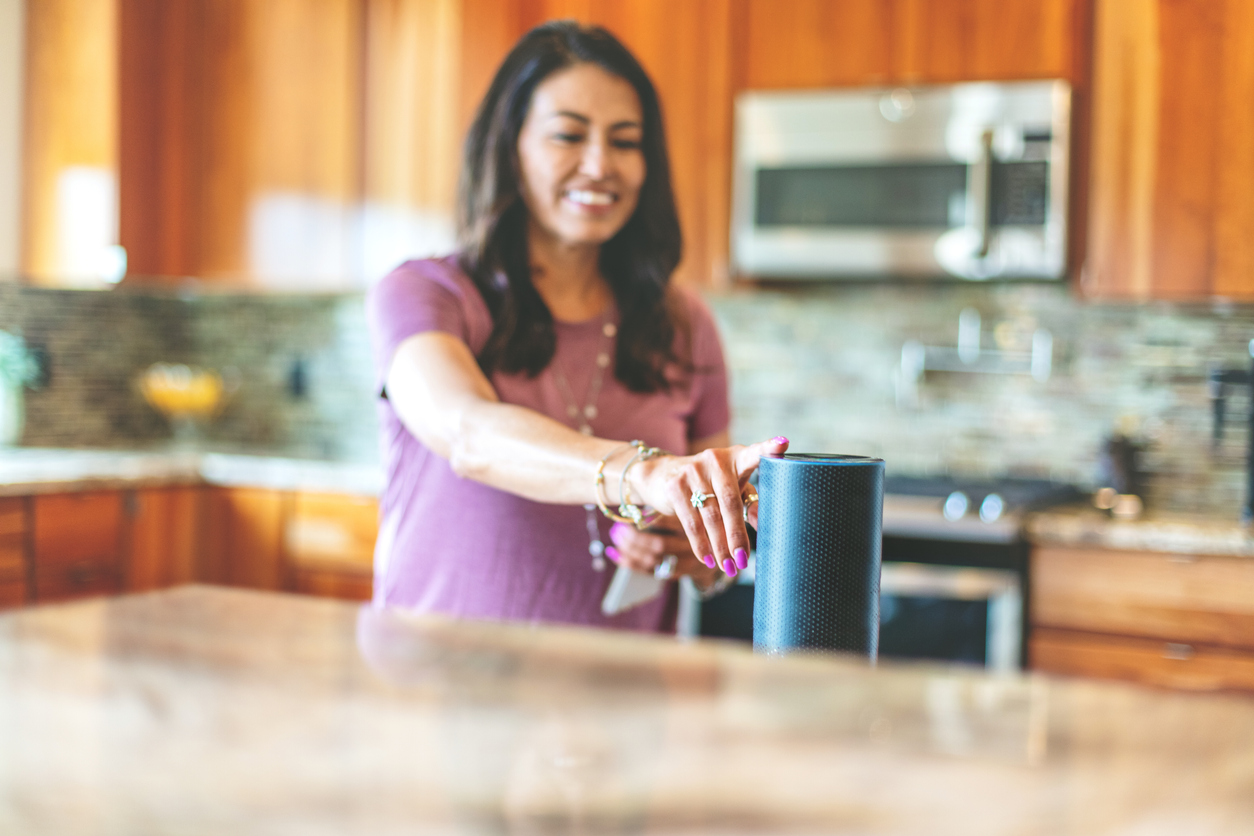 Mature Adult Hispanic Female operating smart speaker devices in her home through the use of smart phone in Western Colorado