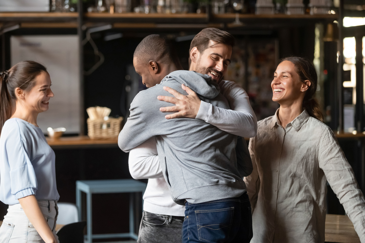 Diverse guys best friends hugging greeting each other at meeting