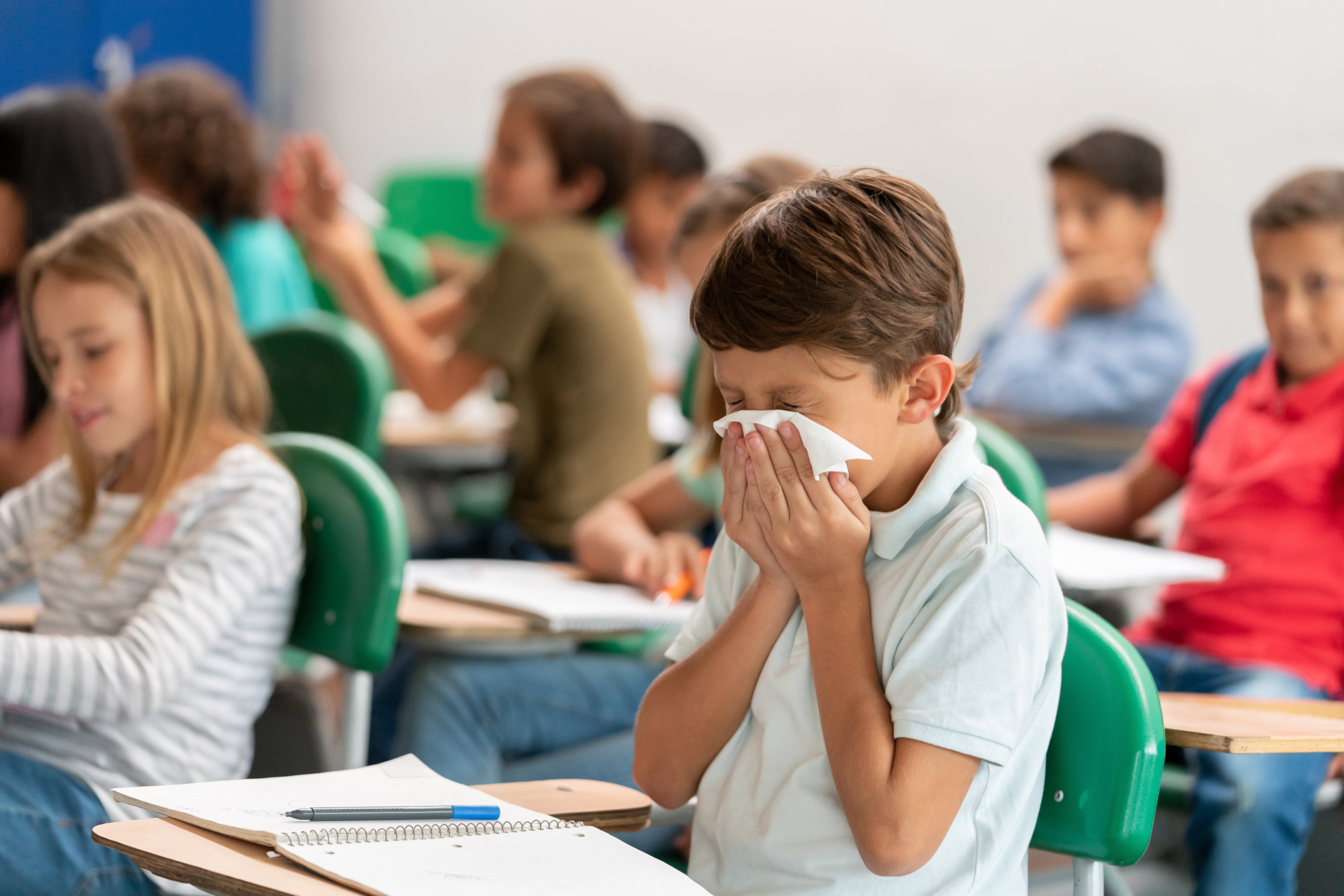 Sick boy at the school blowing his nose in class