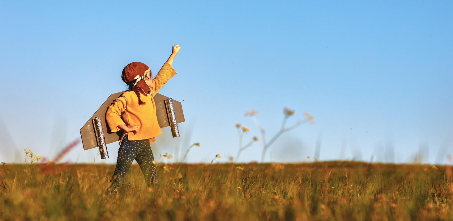 Child pilot aviator with wings of airplane dreams of traveling in summer  at sunset