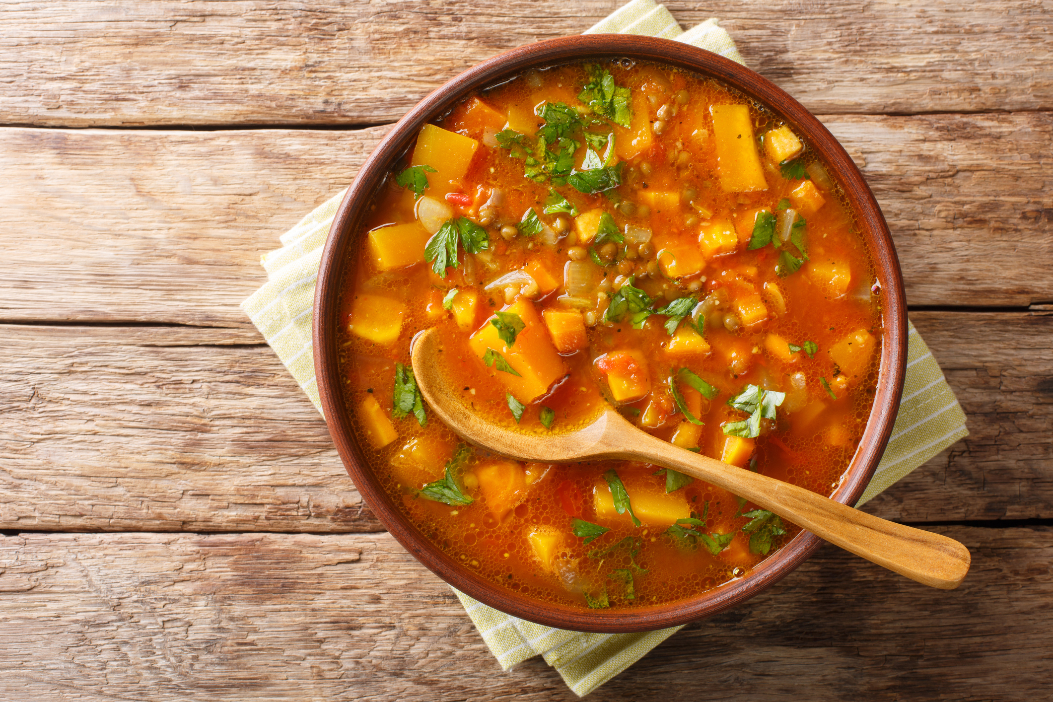 Traditional thick sweet potato soup with lentils close up in a bowl on the table. Horizontal top view