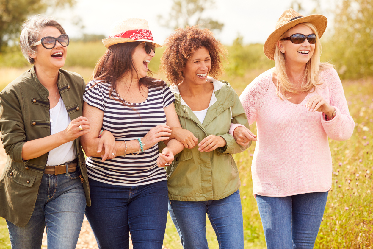 Group Of Mature Female Friends Walking Along Path Through Yurt Campsite