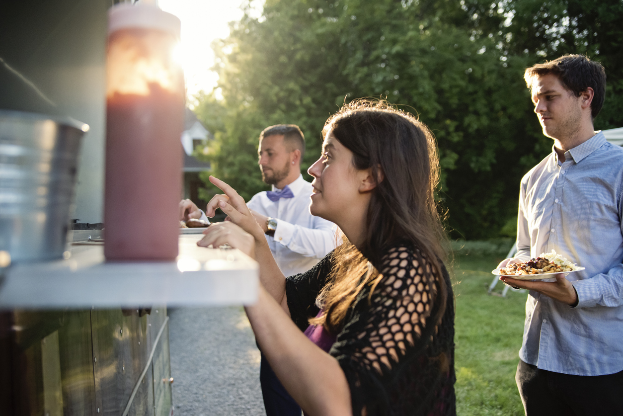 People getting meals from a food truck at a wedding.