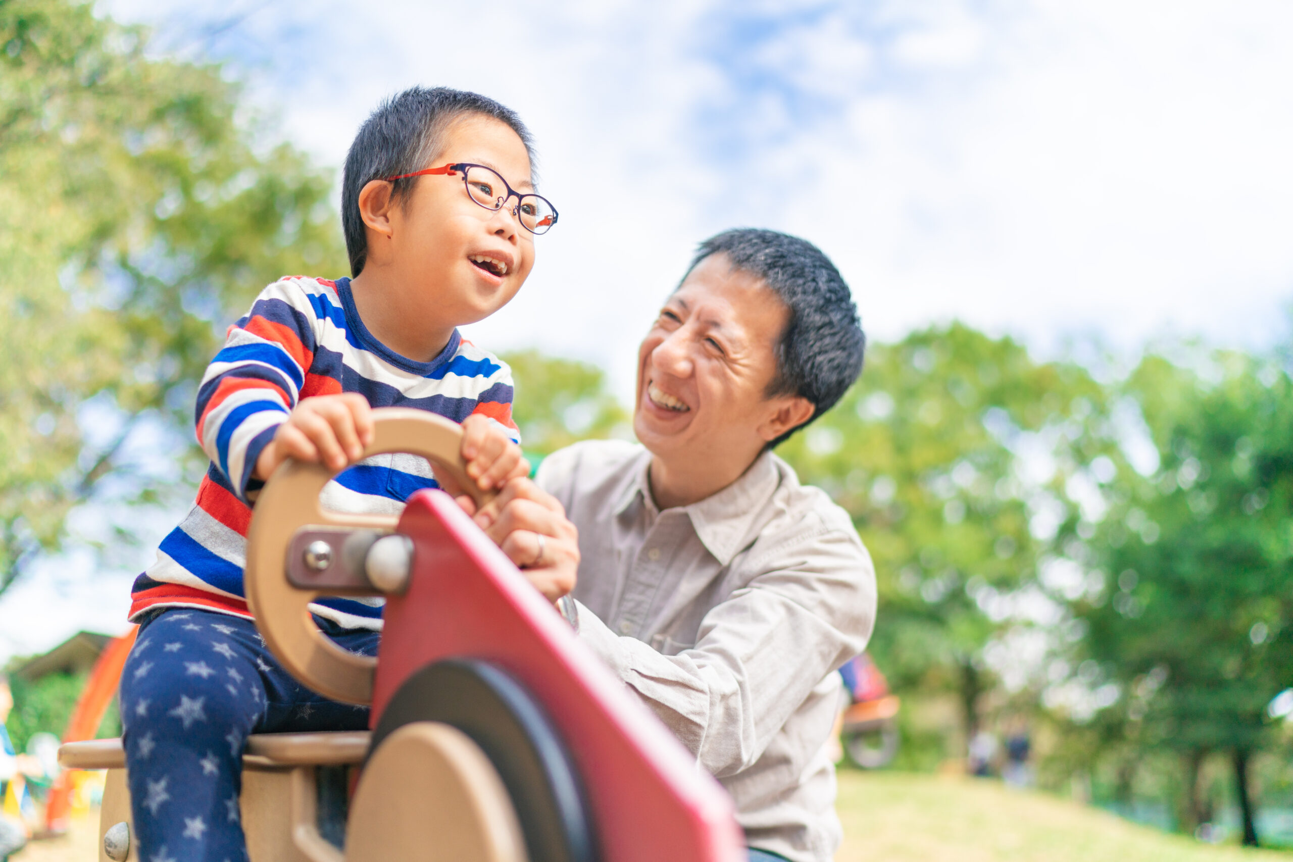 Child with down syndrome enjoying with his father at public park