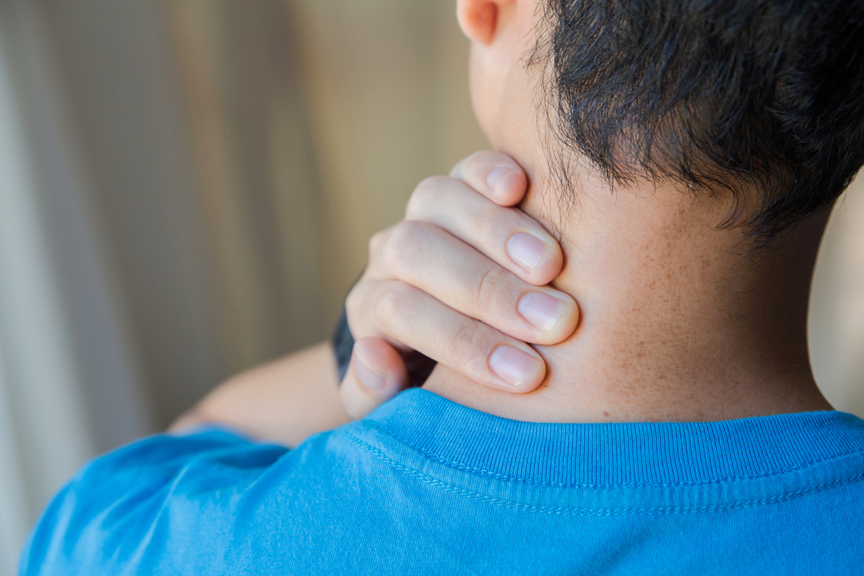 Closeup of man his neck with hand as he aches with pain in the neck