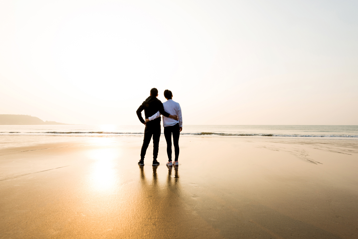 Couple standing at beach with arm around