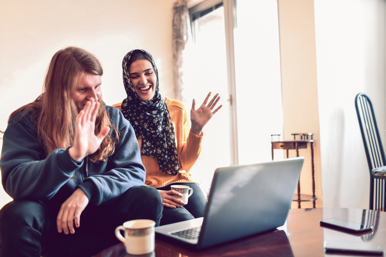 Mixed Couple Watching A Funny Movie On Laptop And Drinking Coffee