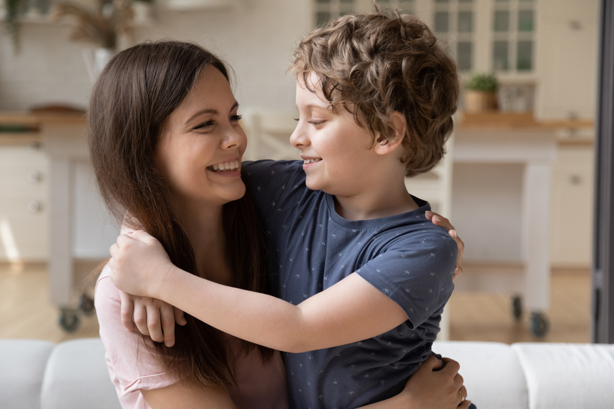 Smiling mother looking at little son, hugging, having fun