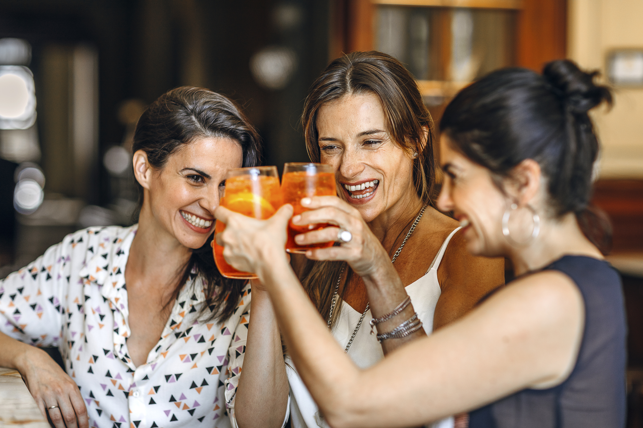 Joyful Latin friends toasting at bar