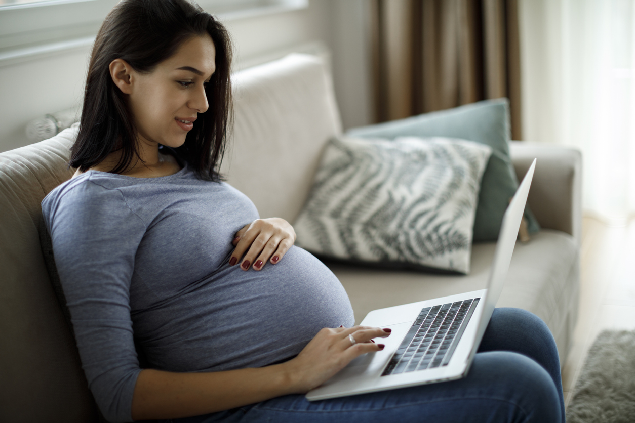 Pregnant woman using laptop at home