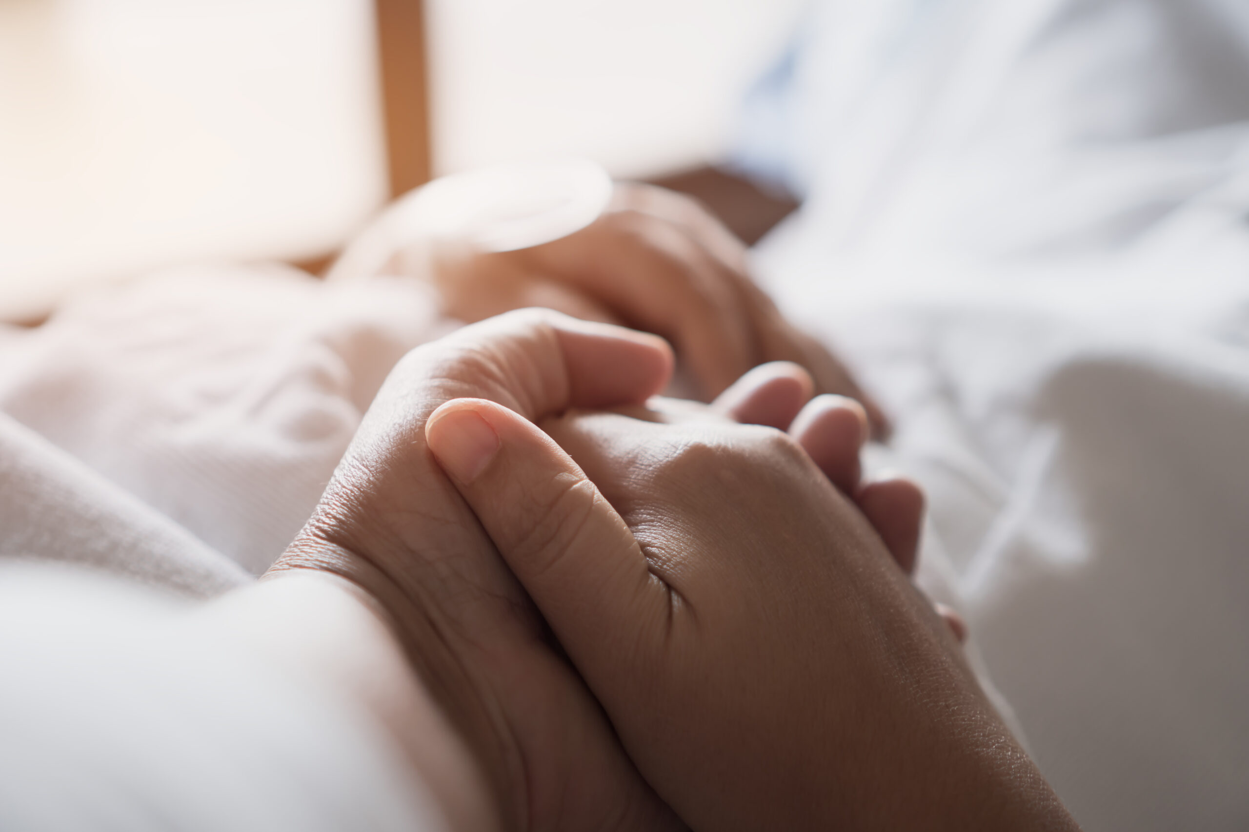 Holding patient's hand in hospital bed