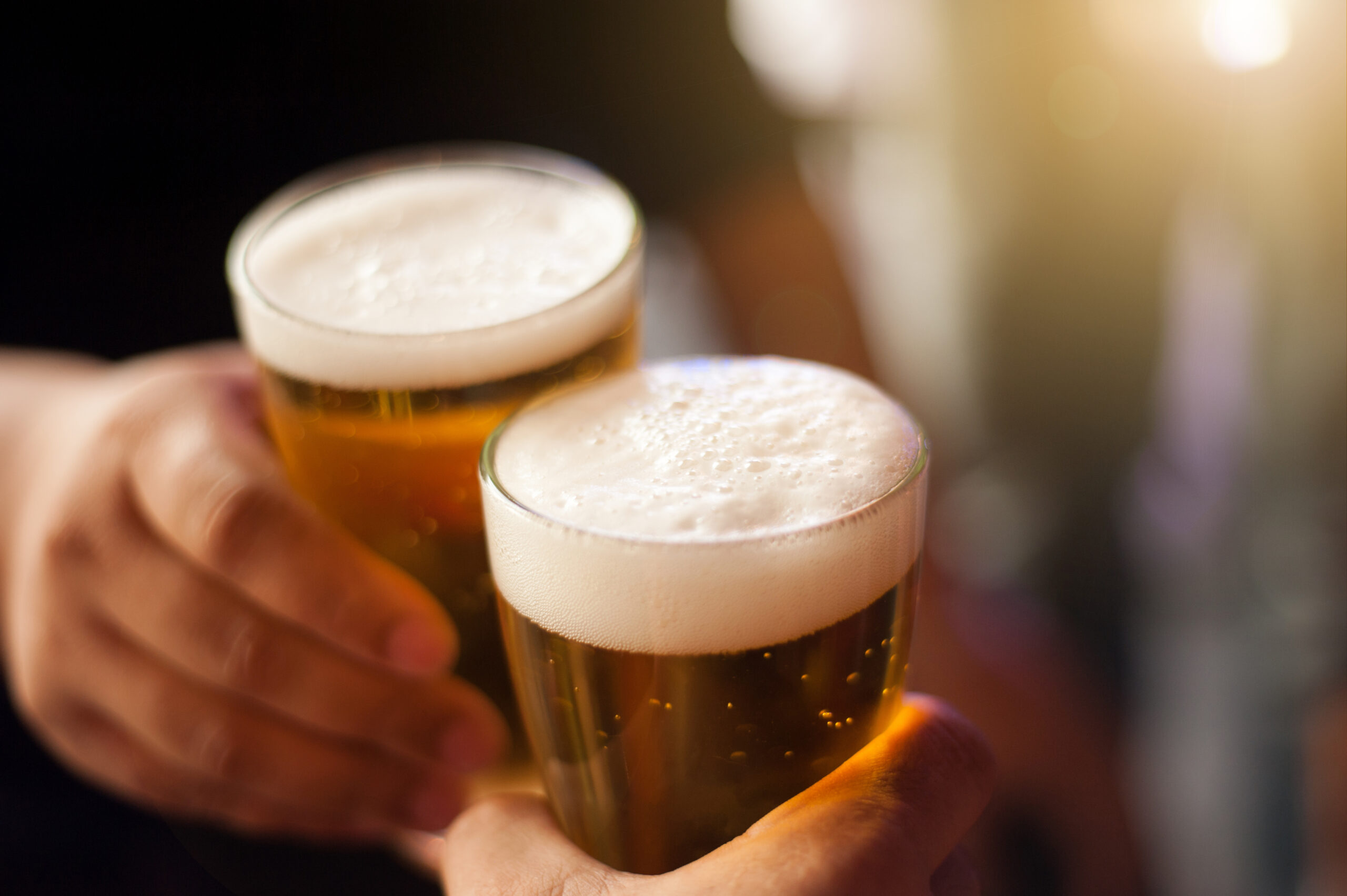 Cheers! Clink glasses. Close-up shots of hands holding beer glasses and beer bubbles.