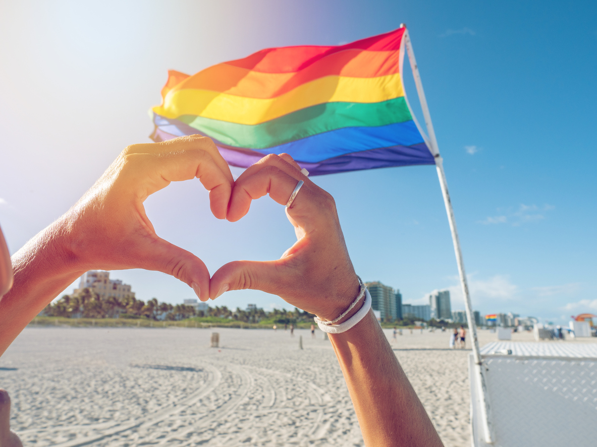 Hands making heart with hands on gay rainbow flag, Miami Beach