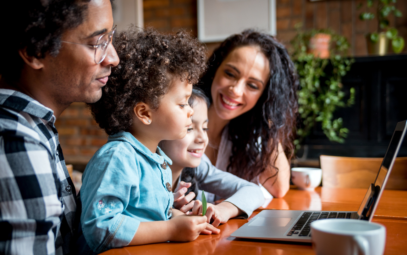 Happy multiethnic family having fun while using laptop together