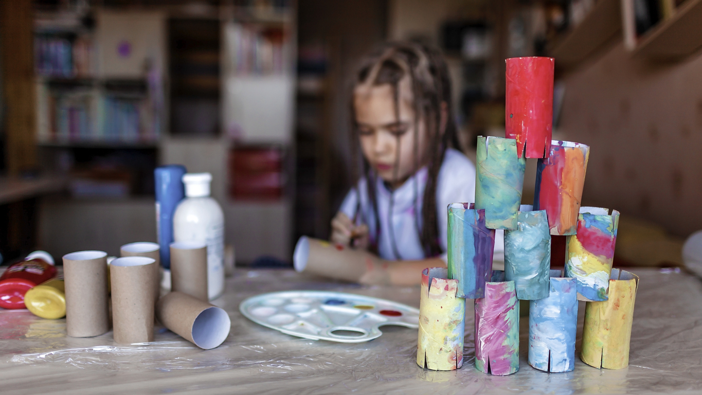 Cute girl coloring toilet paper rolls to use them like paper blocks to build a tower