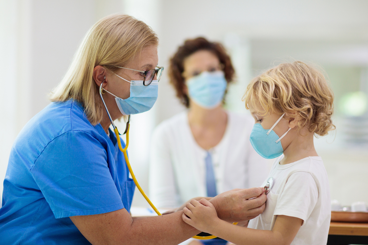 Doctor examining sick child in face mask