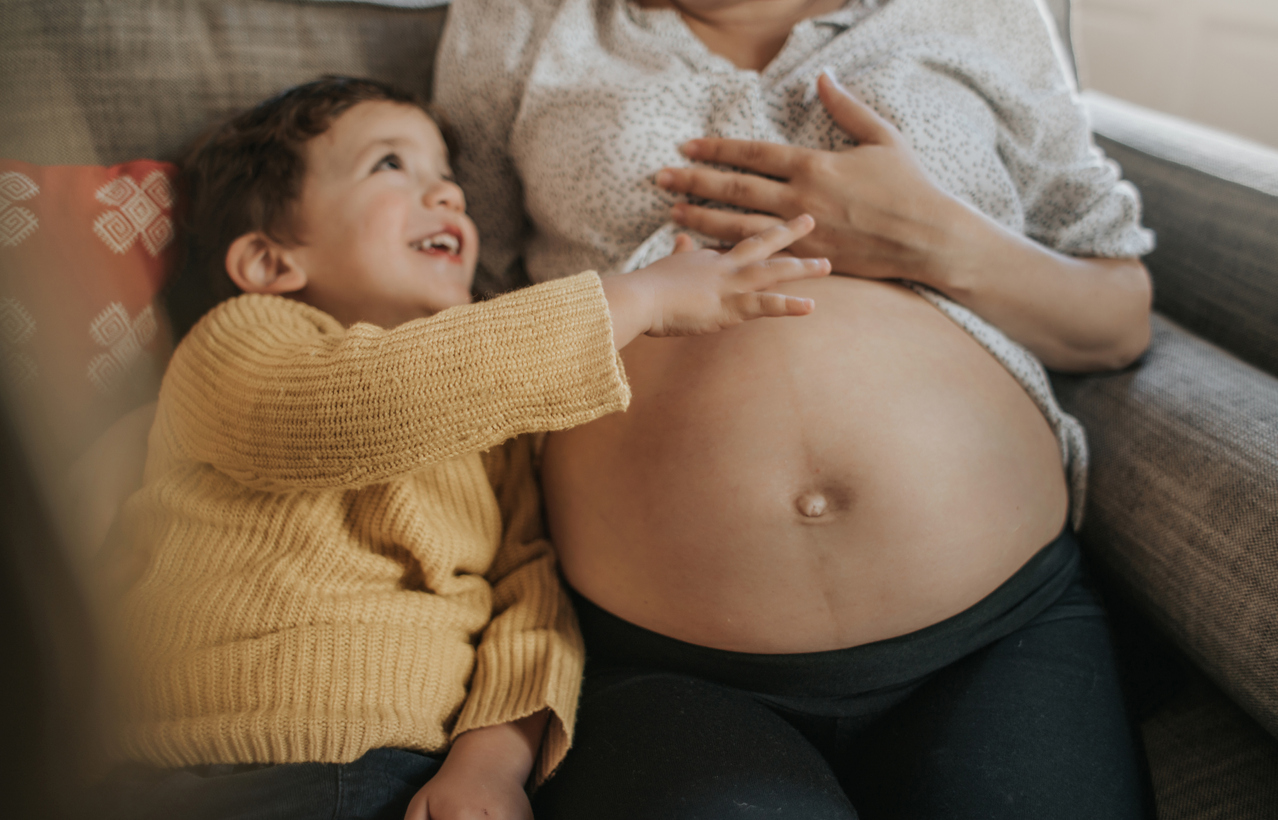 Boy touching his pregnant mother's belly