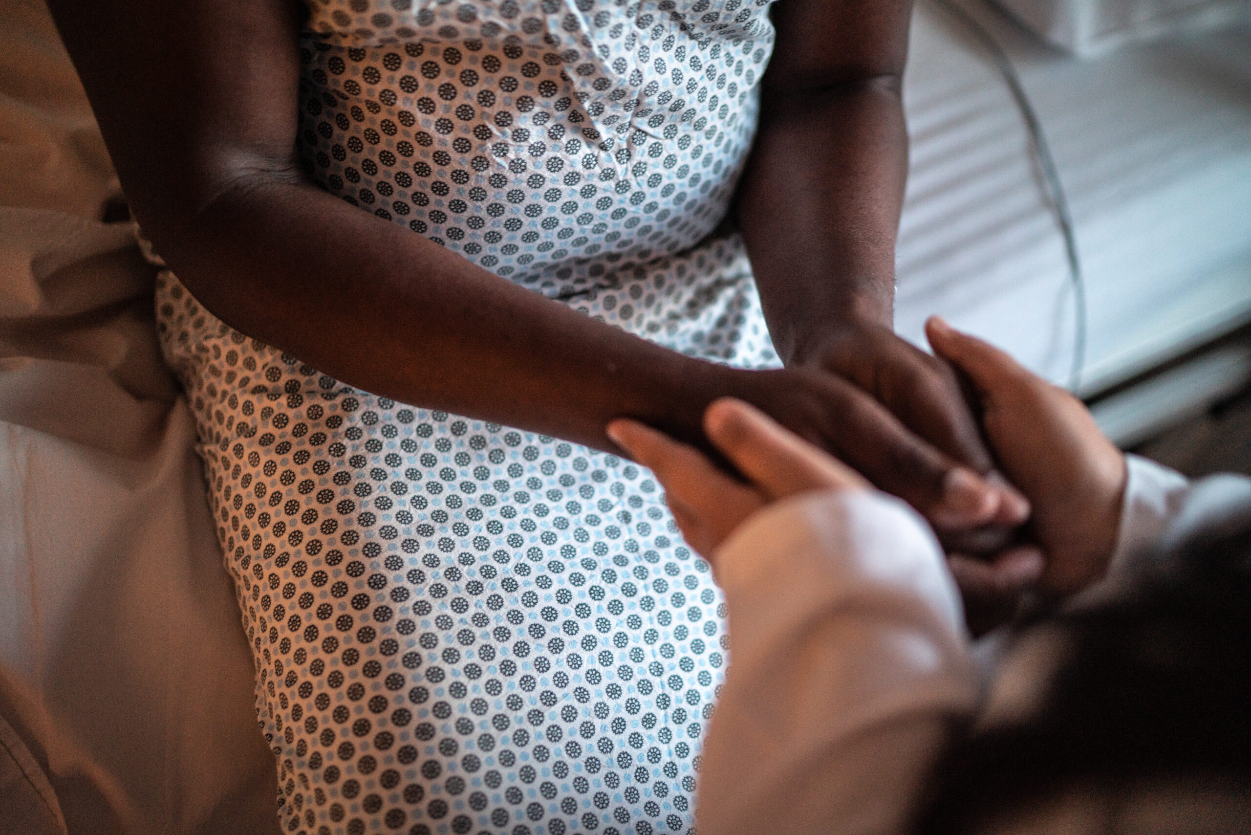 Female doctor holding hands of her patient at hospital room