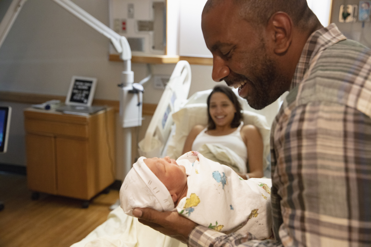 Father holding newborn baby at hospital