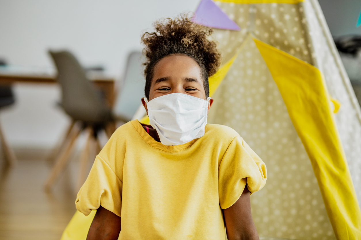 Little African American girl smiling with face mask indoors