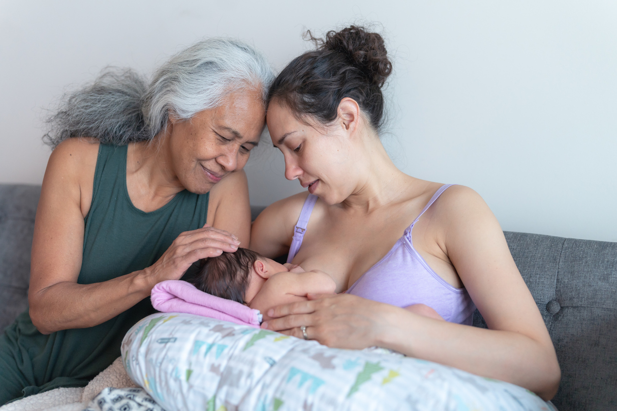 A new young mother gets encouragement from her mom while breastfeeding her infant daughter