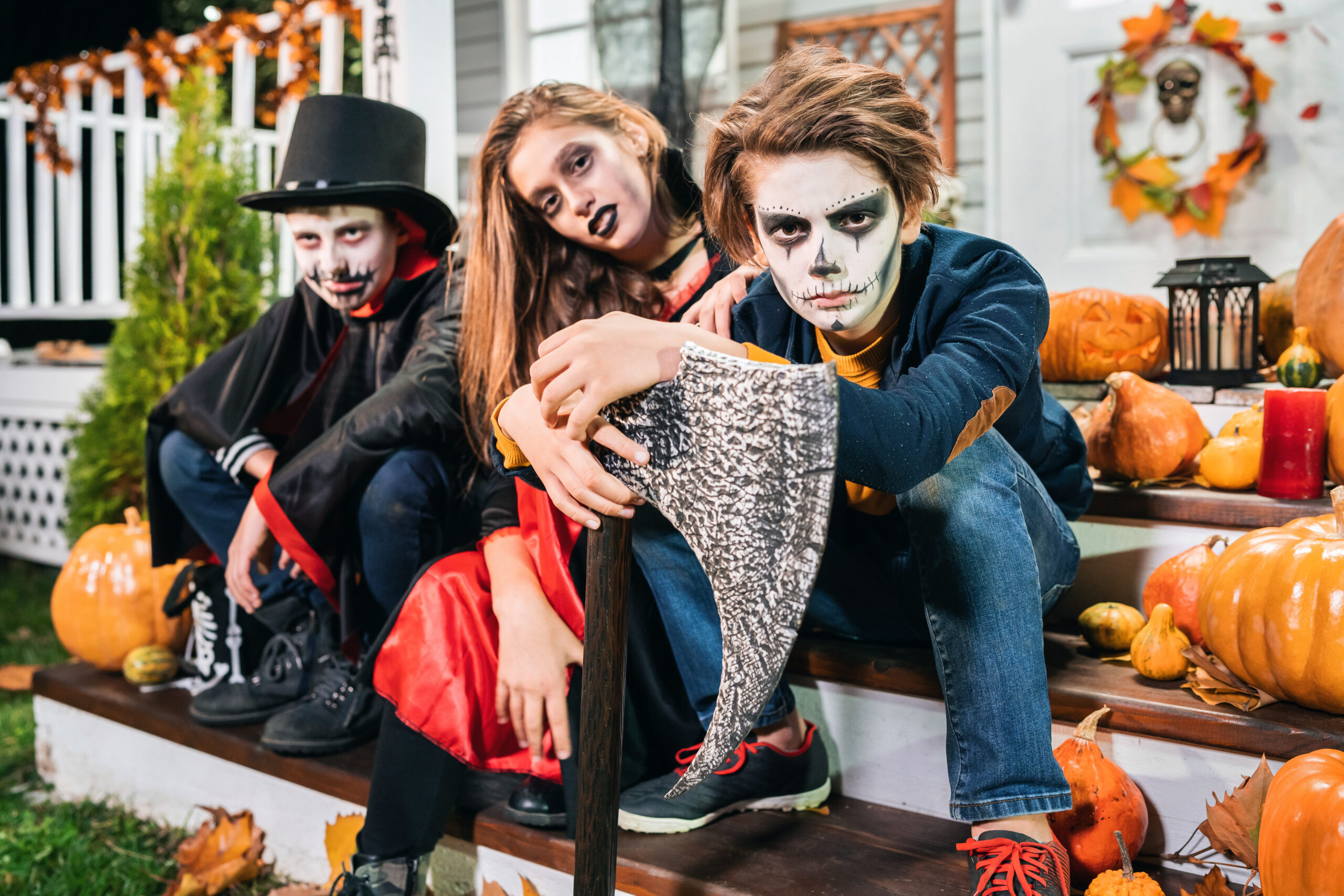 Kids dressed in Halloween costumes sitting on the stairs in front of the house trick or treat