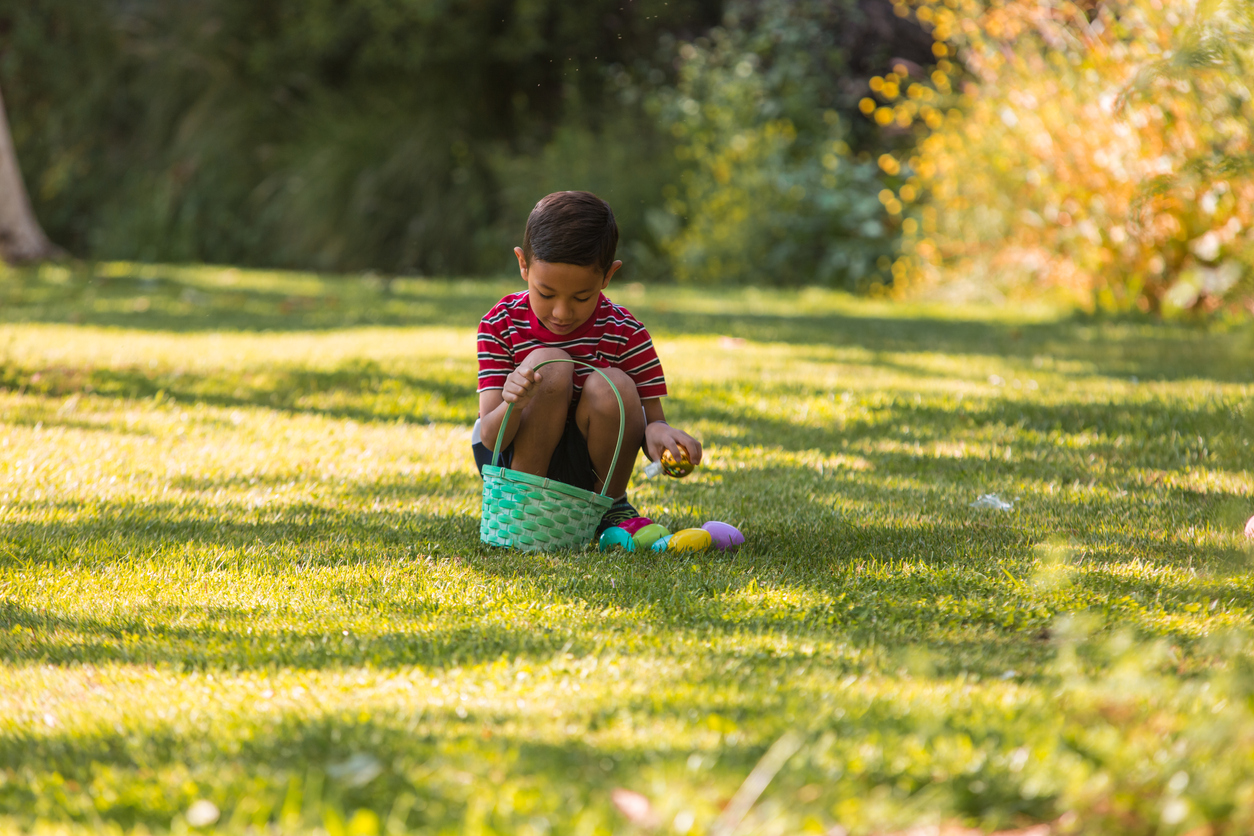 Boy during Easter looking for eggs at a park hunting