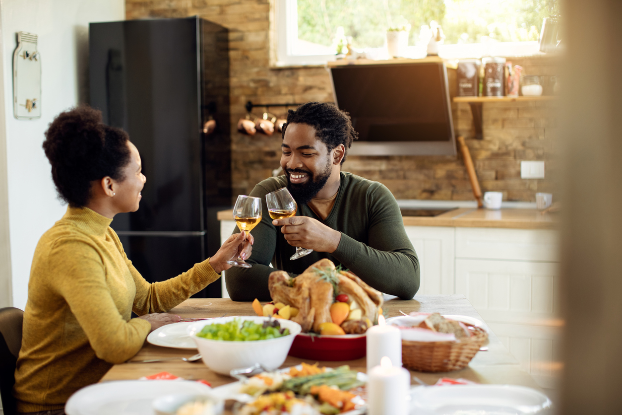 Happy African American couple toasting during Thanksgiving meal in dining room.