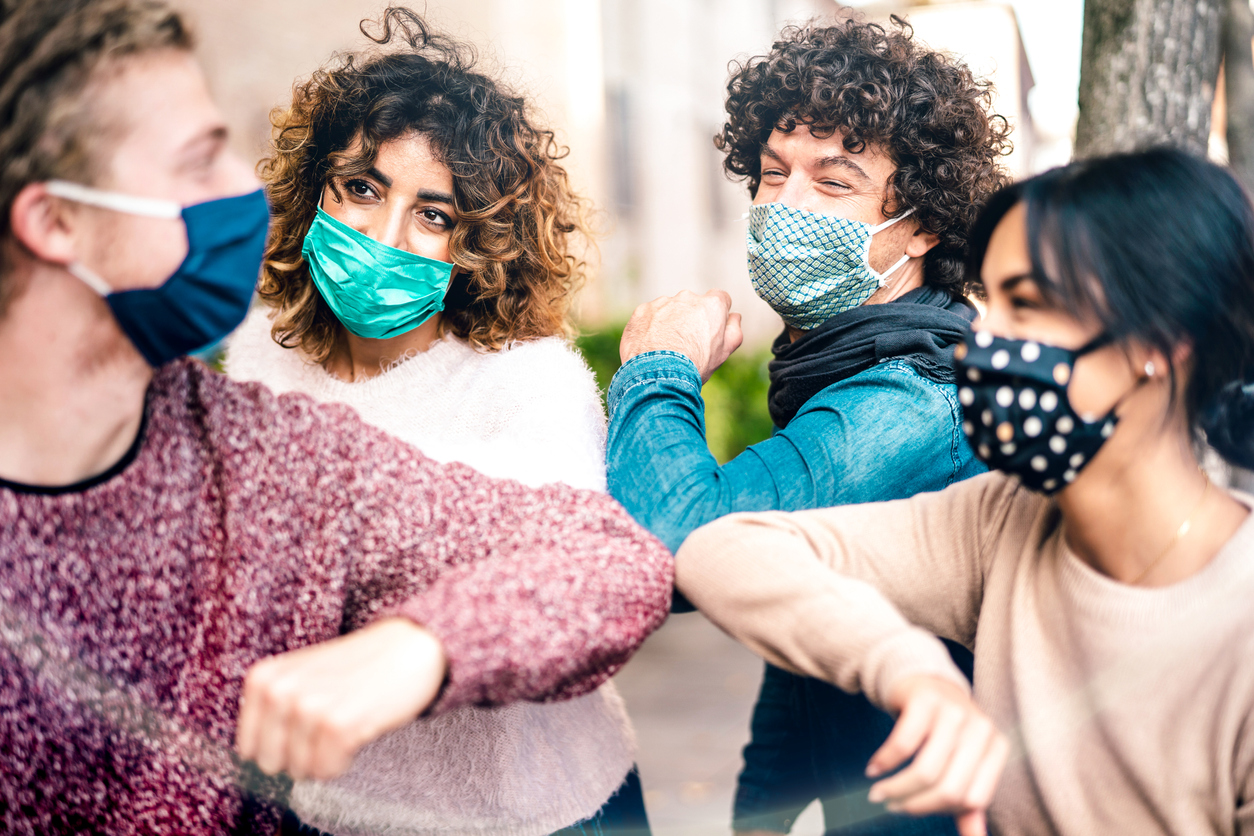 Multiracial friends greeting with elbow bump wearing face protection - New normal lifestyle concept with young people covered by disposable mask - Selective focus on middle left woman