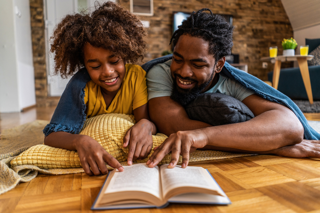 Happy father and daughter reading a book together.