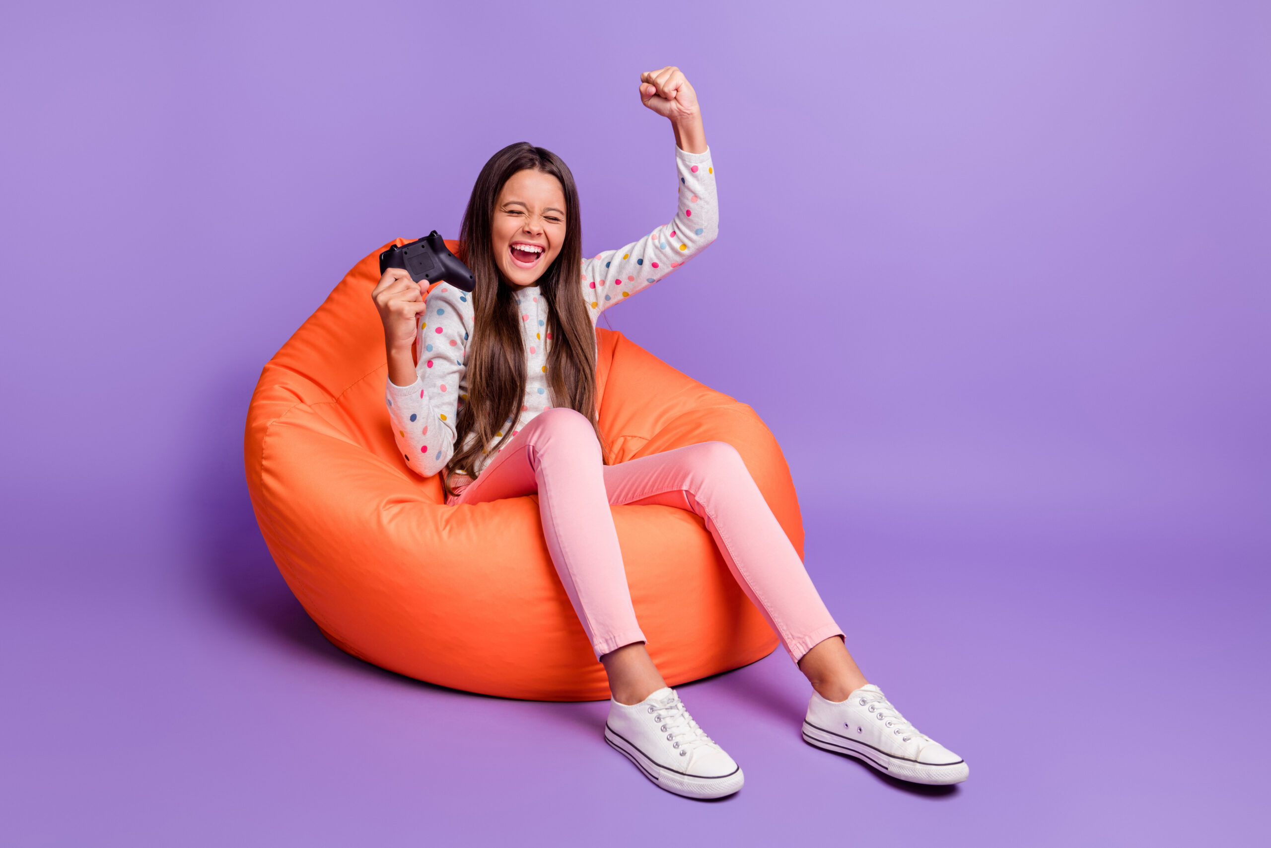 Full length body size photo of little girl playing video games gesturing like winner keeping joystick isolated on bright violet background