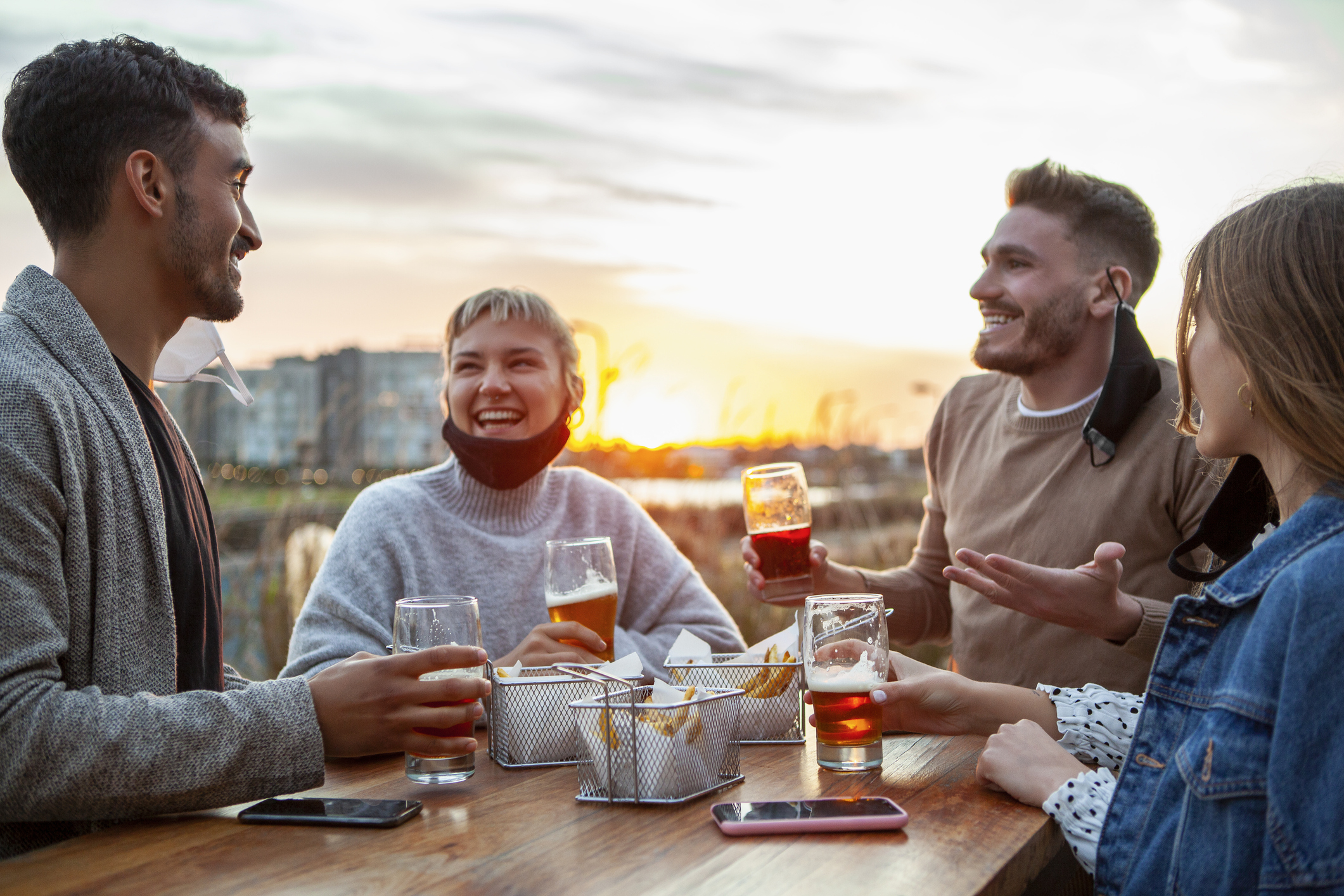 Happy friends with beer glassesduring sunset