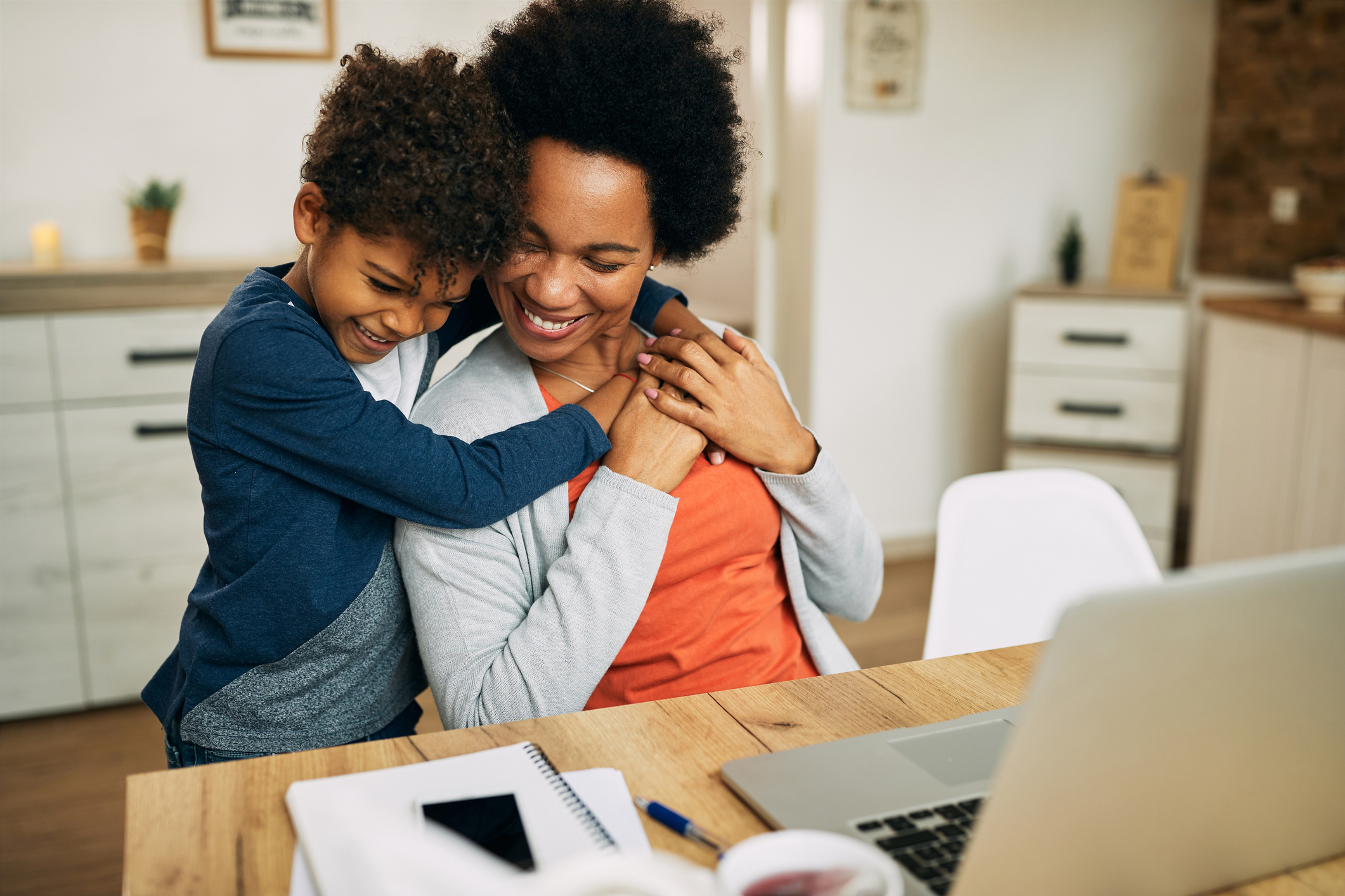 Happy African American mother and son embracing at home.