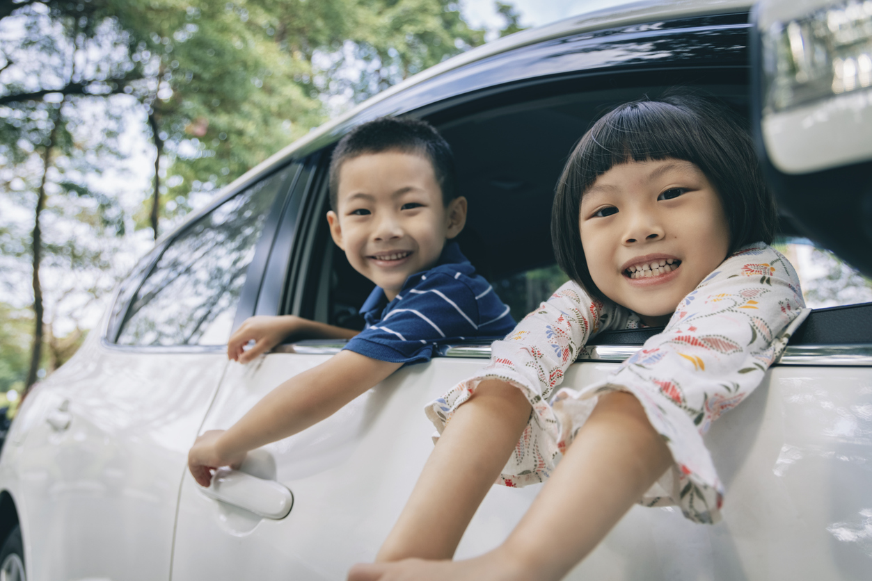 Happy little girl and boy sitting in the car