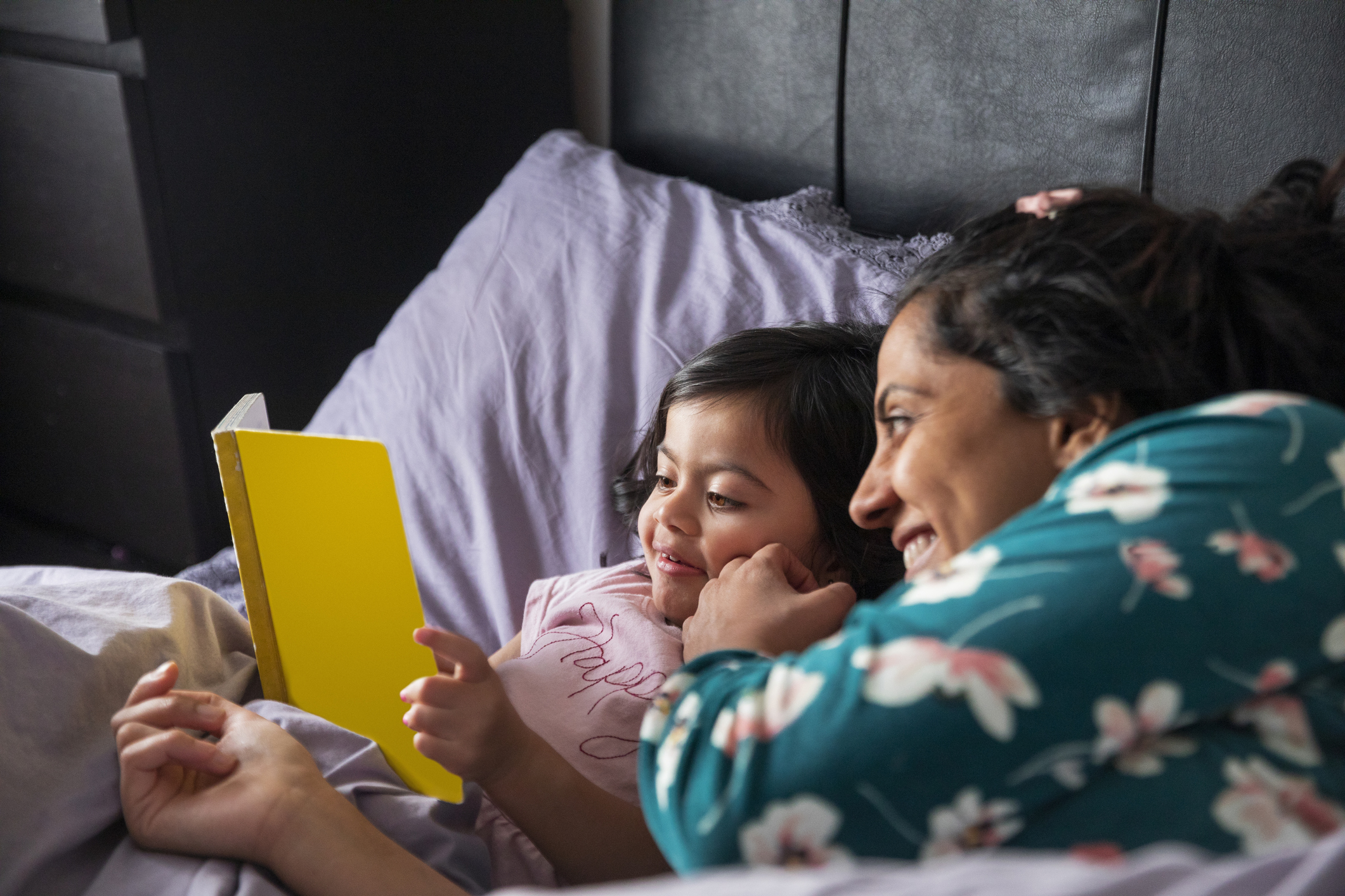 Mother and Daughter Reading a Book in Bed