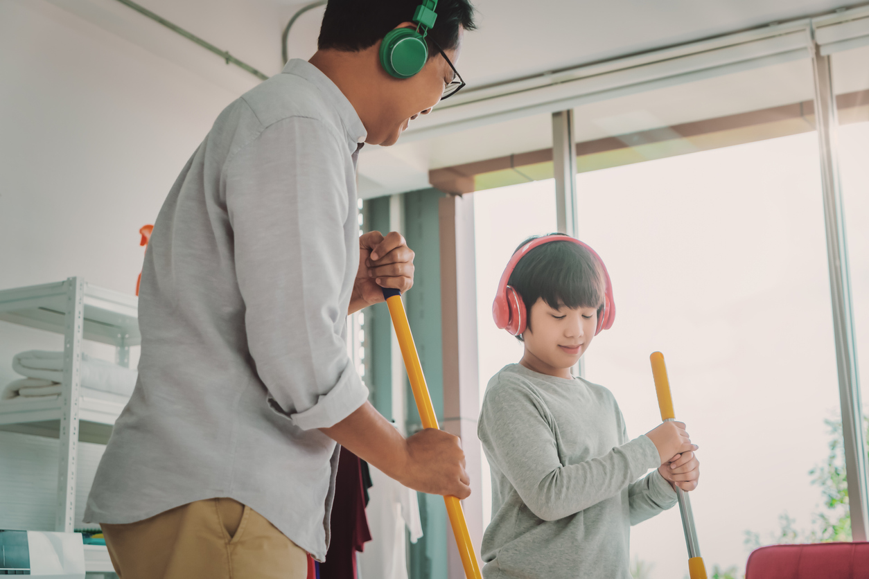 Father and son is wearing Music headphone while doing house cleaning with joy and happiness, for Family togetherness cocnept.