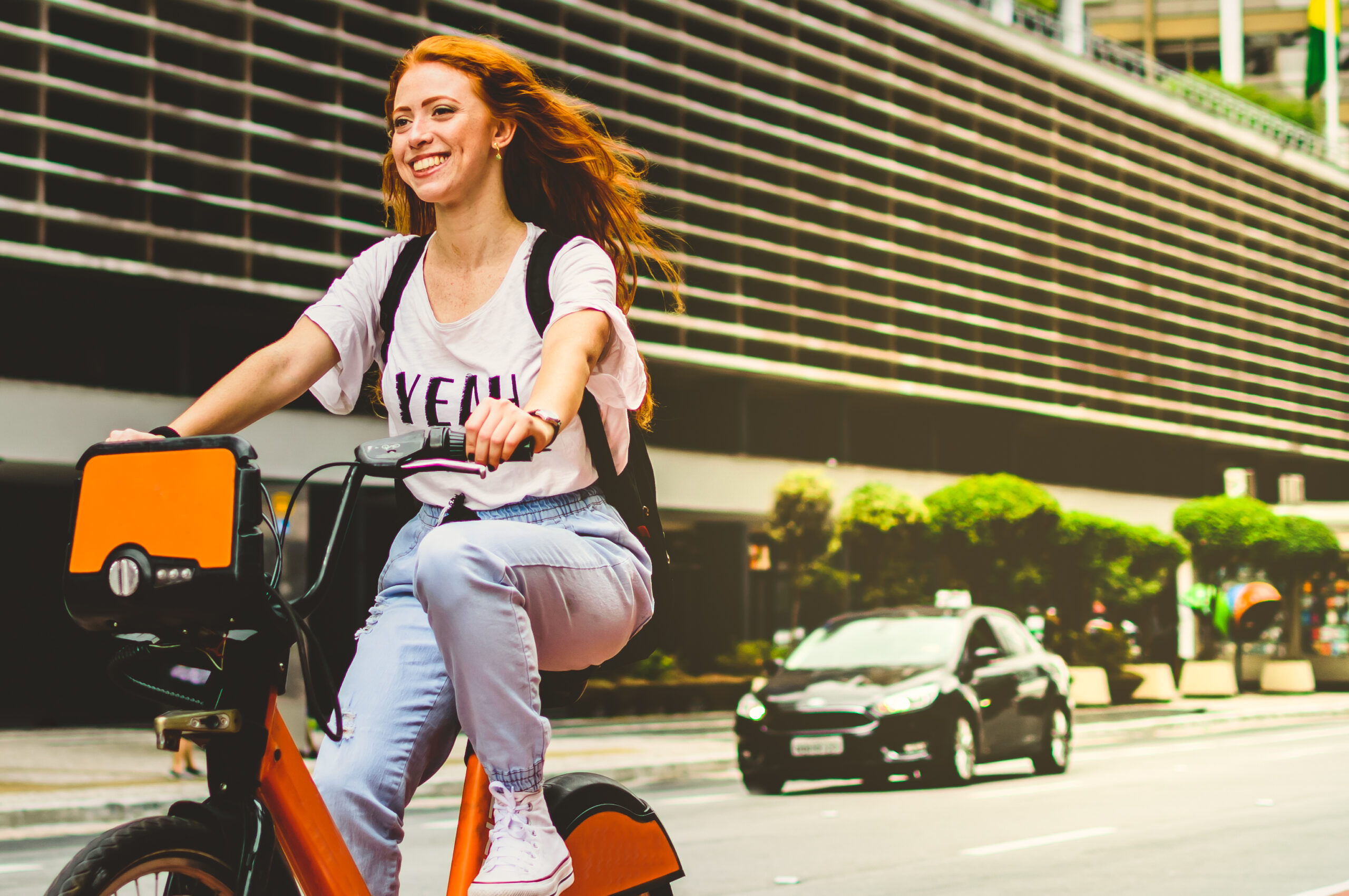 a woman smiling while riding a bicycle in são paulo