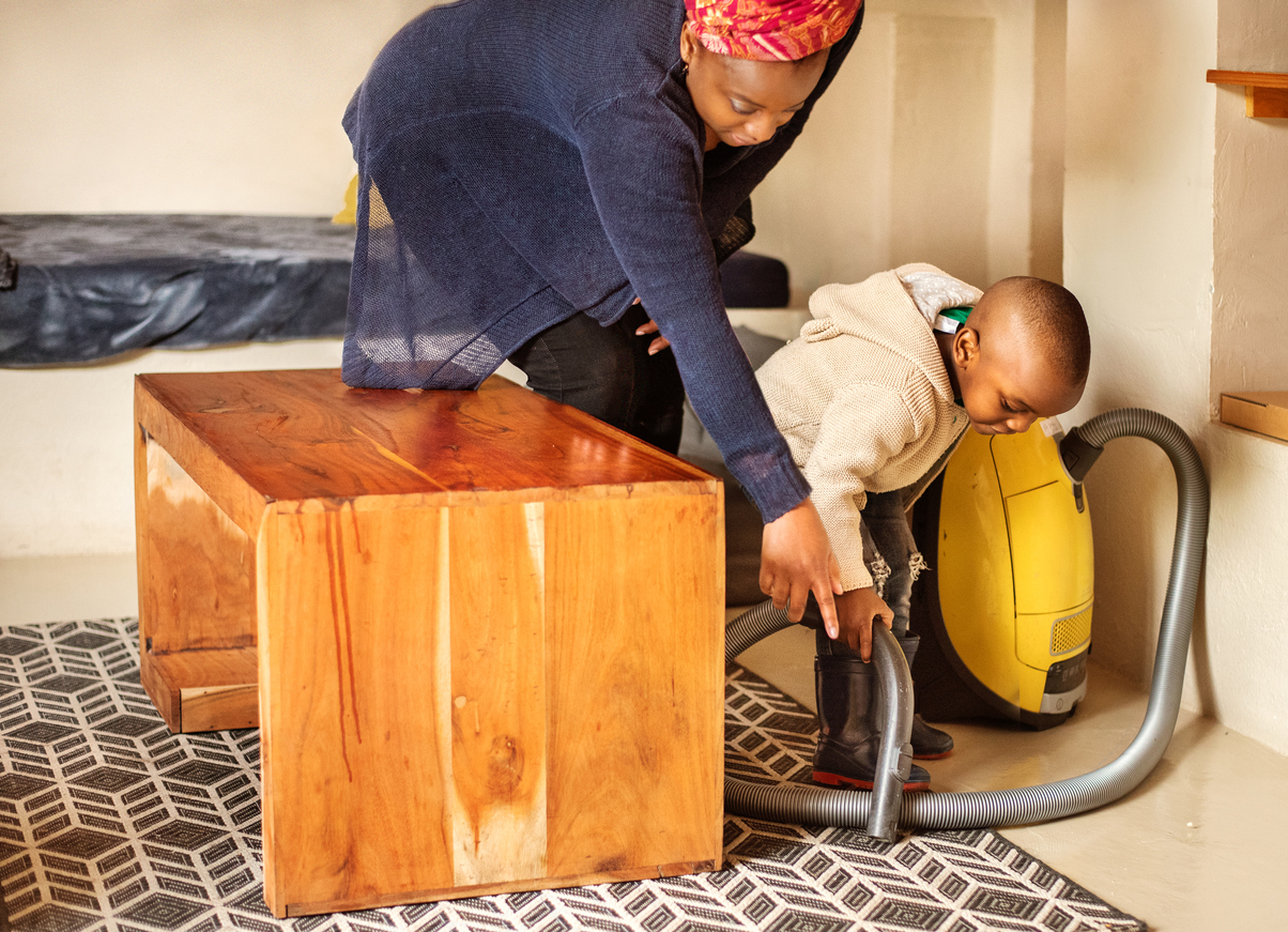 Cute little boy helping his mom vacuum the living room