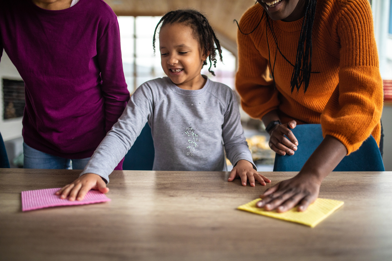 Sisters helping mother with cleaning at home