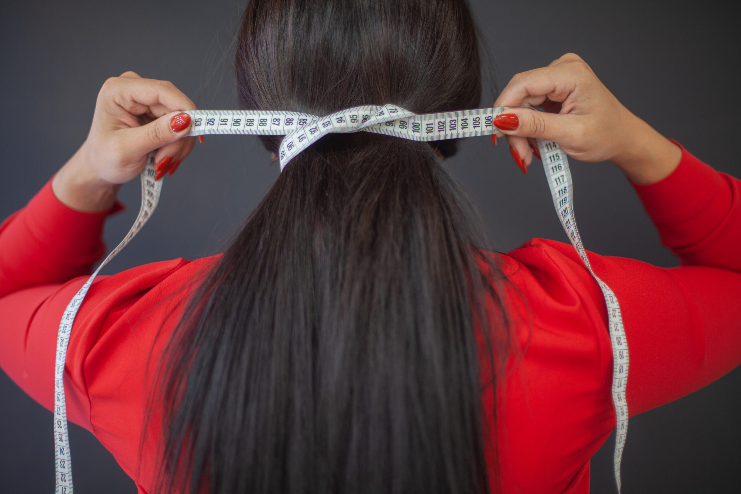 Female fashion designer in red dress wrapped her hair with tape measure