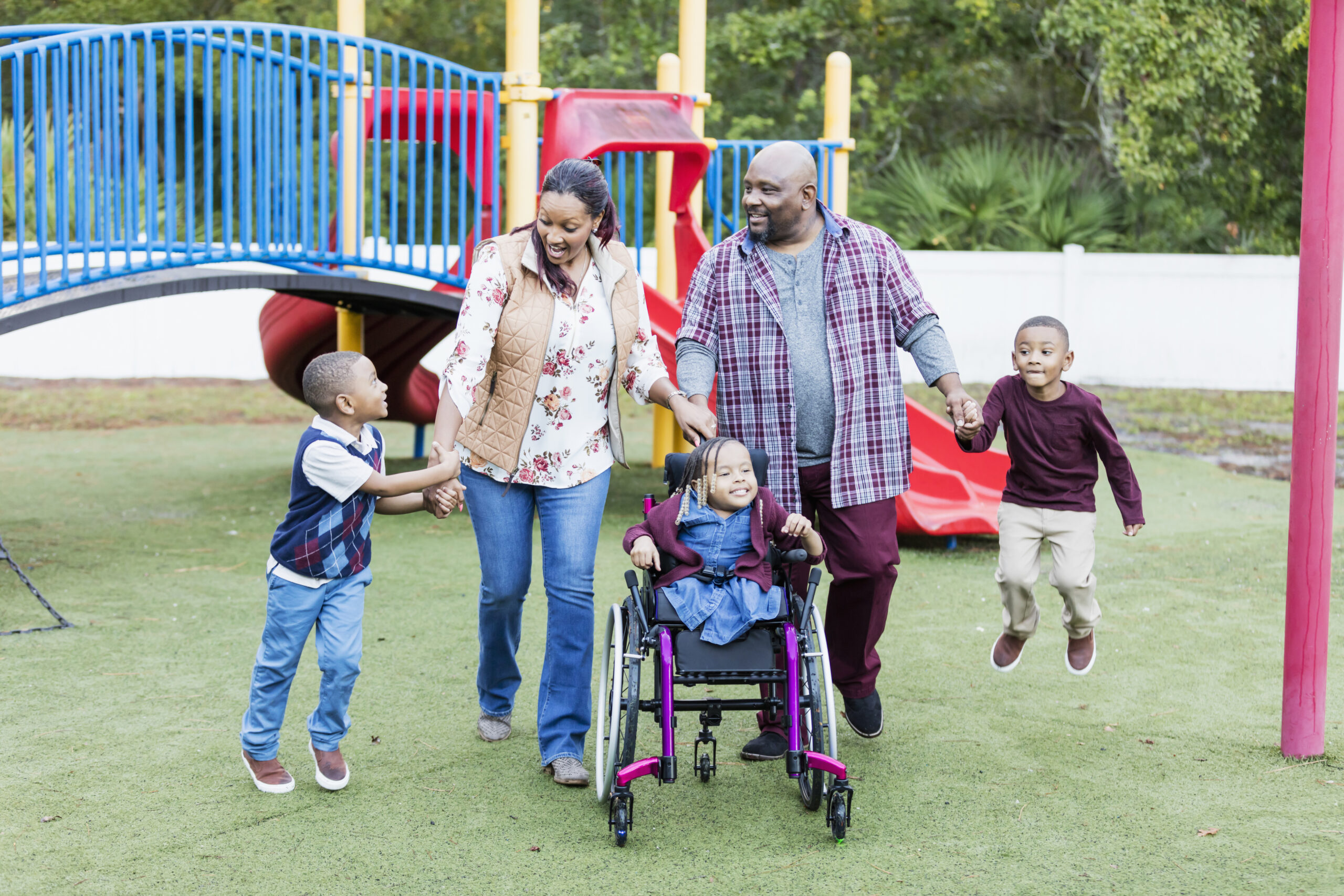 Family walk at playground, girl in wheelchair, twin boys