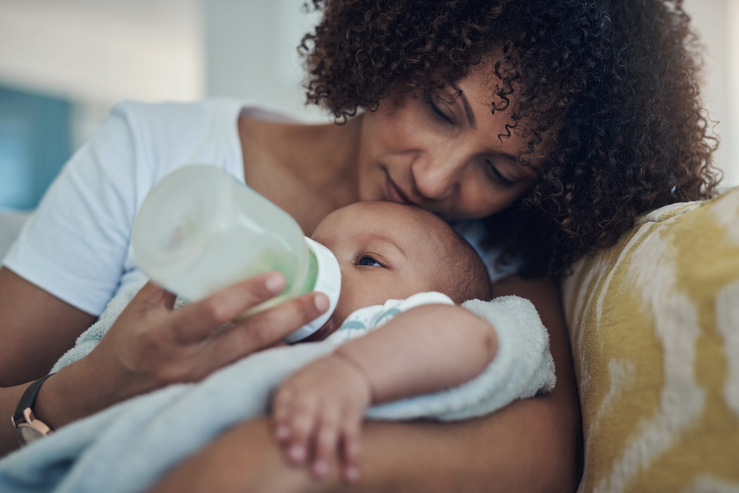 Shot of an adorable baby girl being bottle fed by her mother on the sofa at home