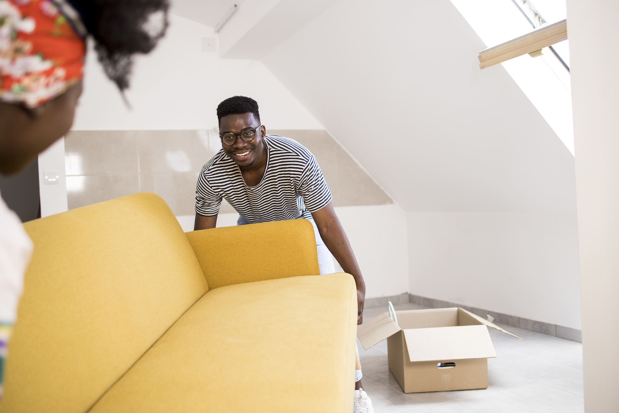 Happy African American man and his wife carrying a new sofa into their new home