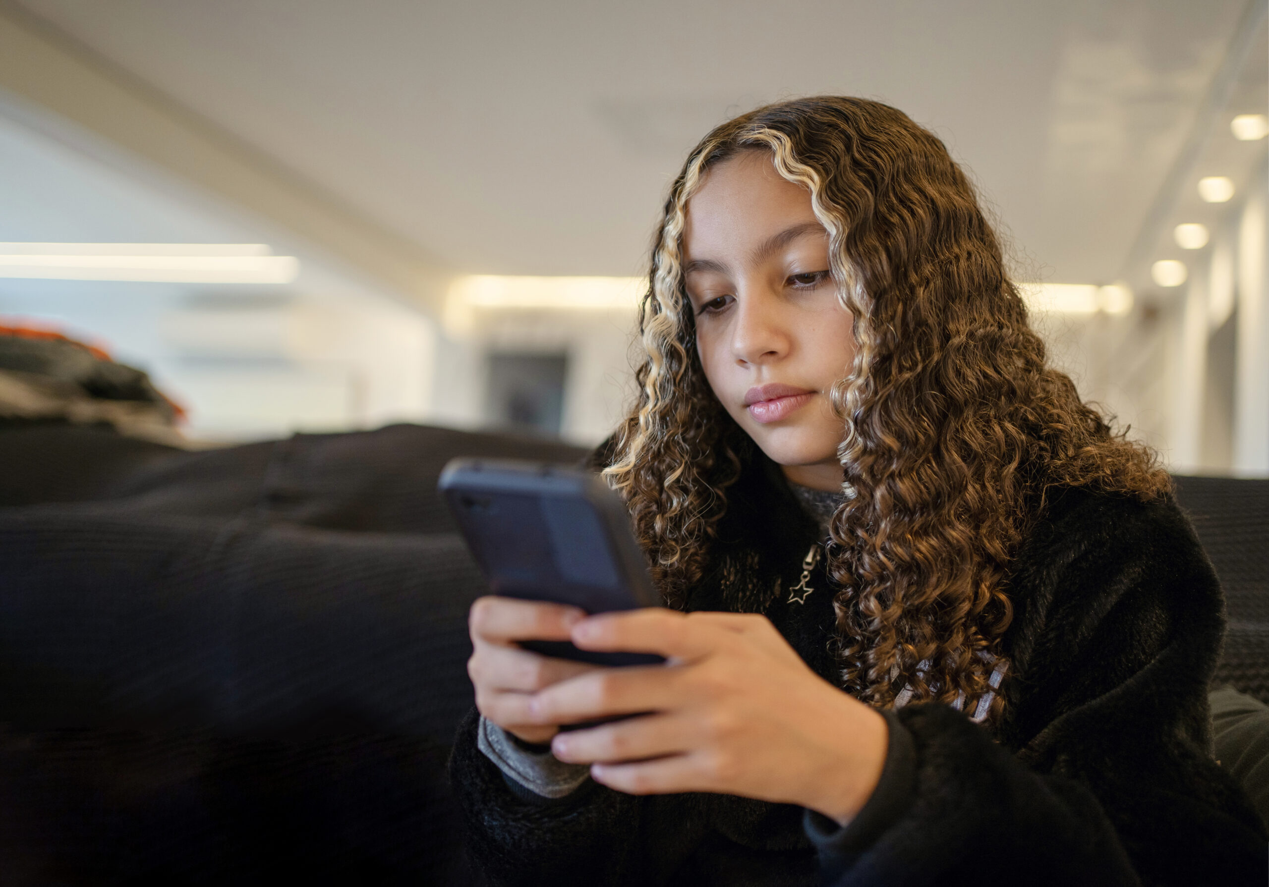 Teen girl using social media on smart phone  on the sofa.