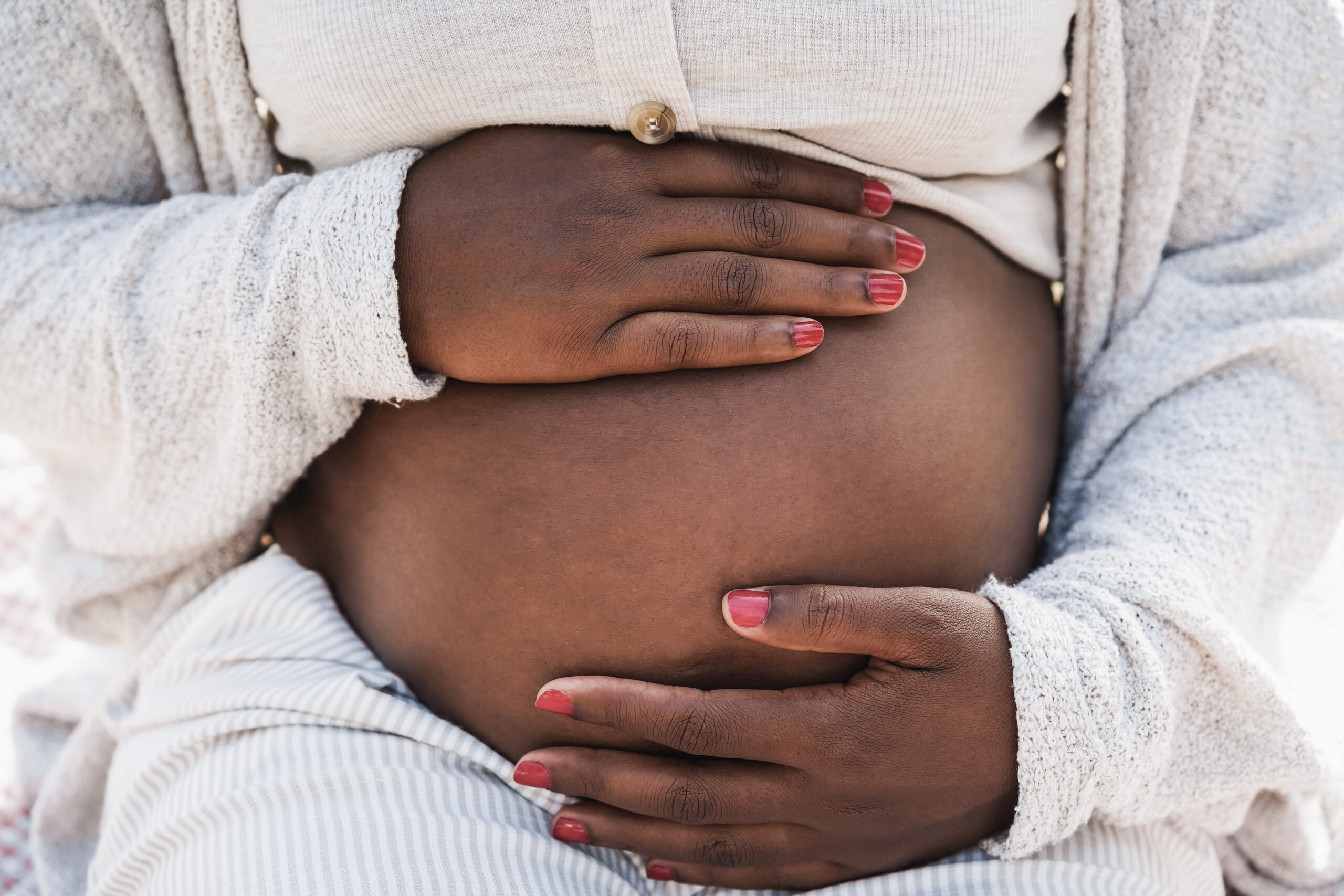 Close up of african pregnant woman holding her belly - Focus on hands