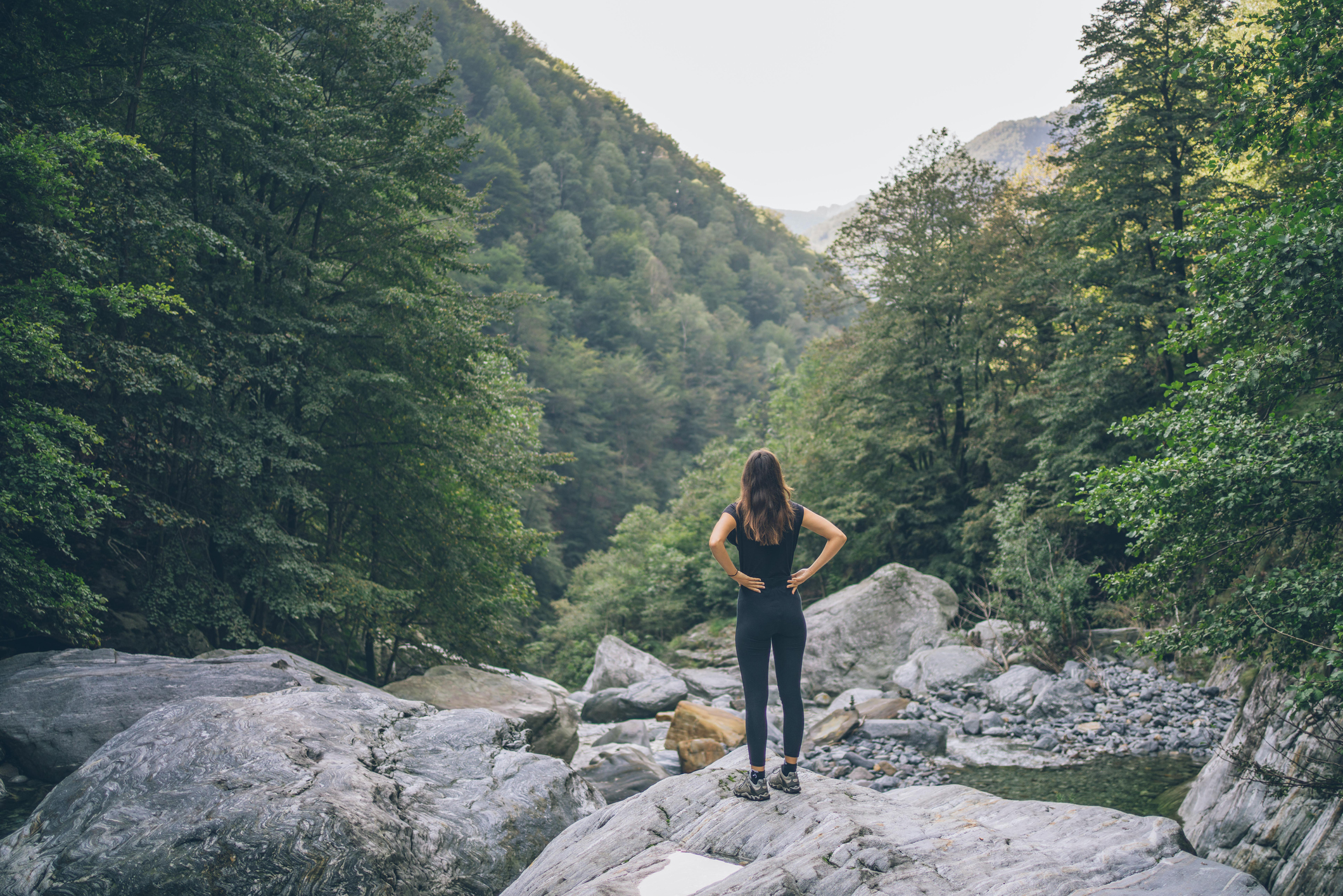 Female hiker relaxes on rock by autumnal forest