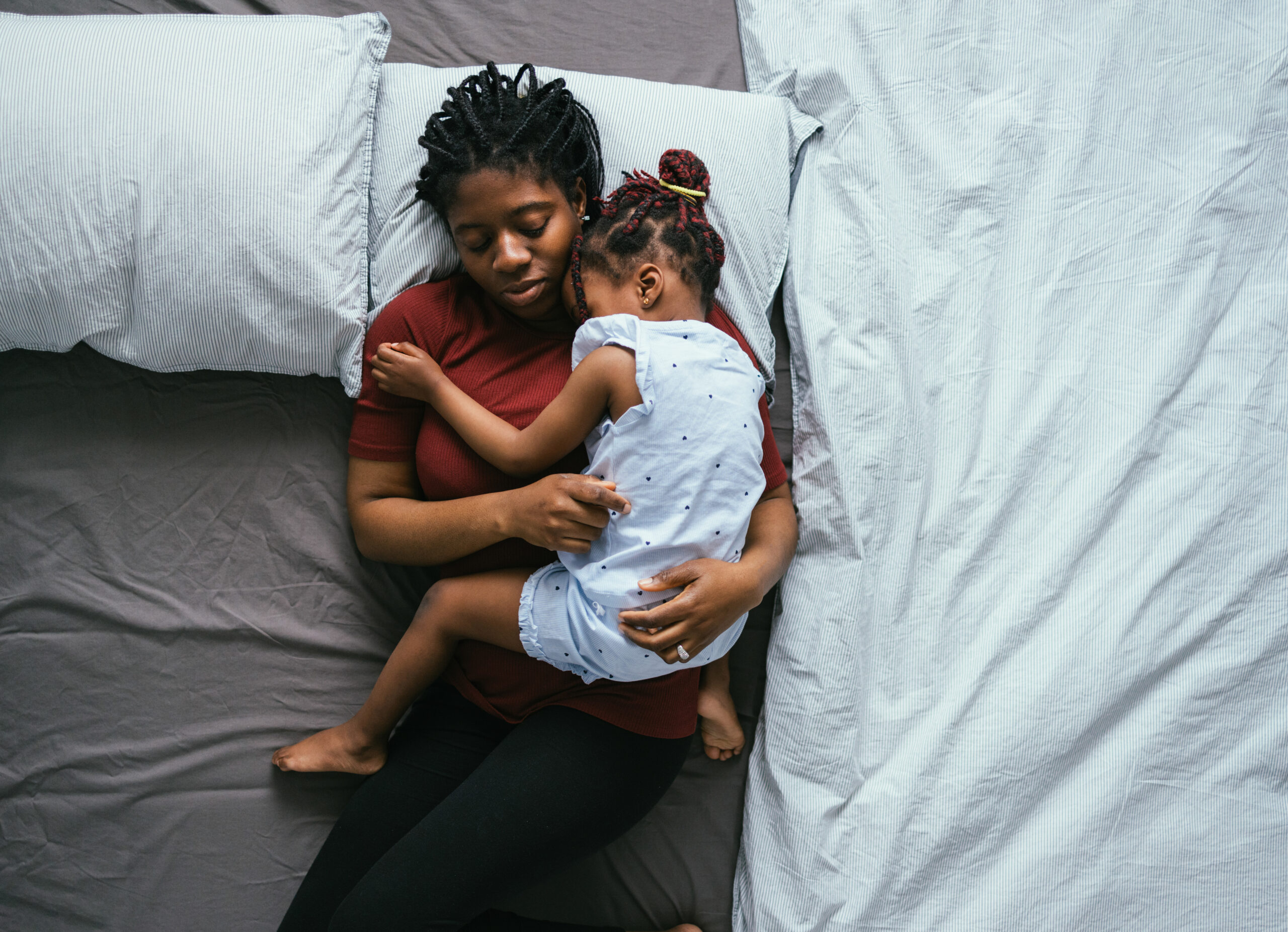 Top View of Beautiful Mother with Little Daughter Sleeping in Bed