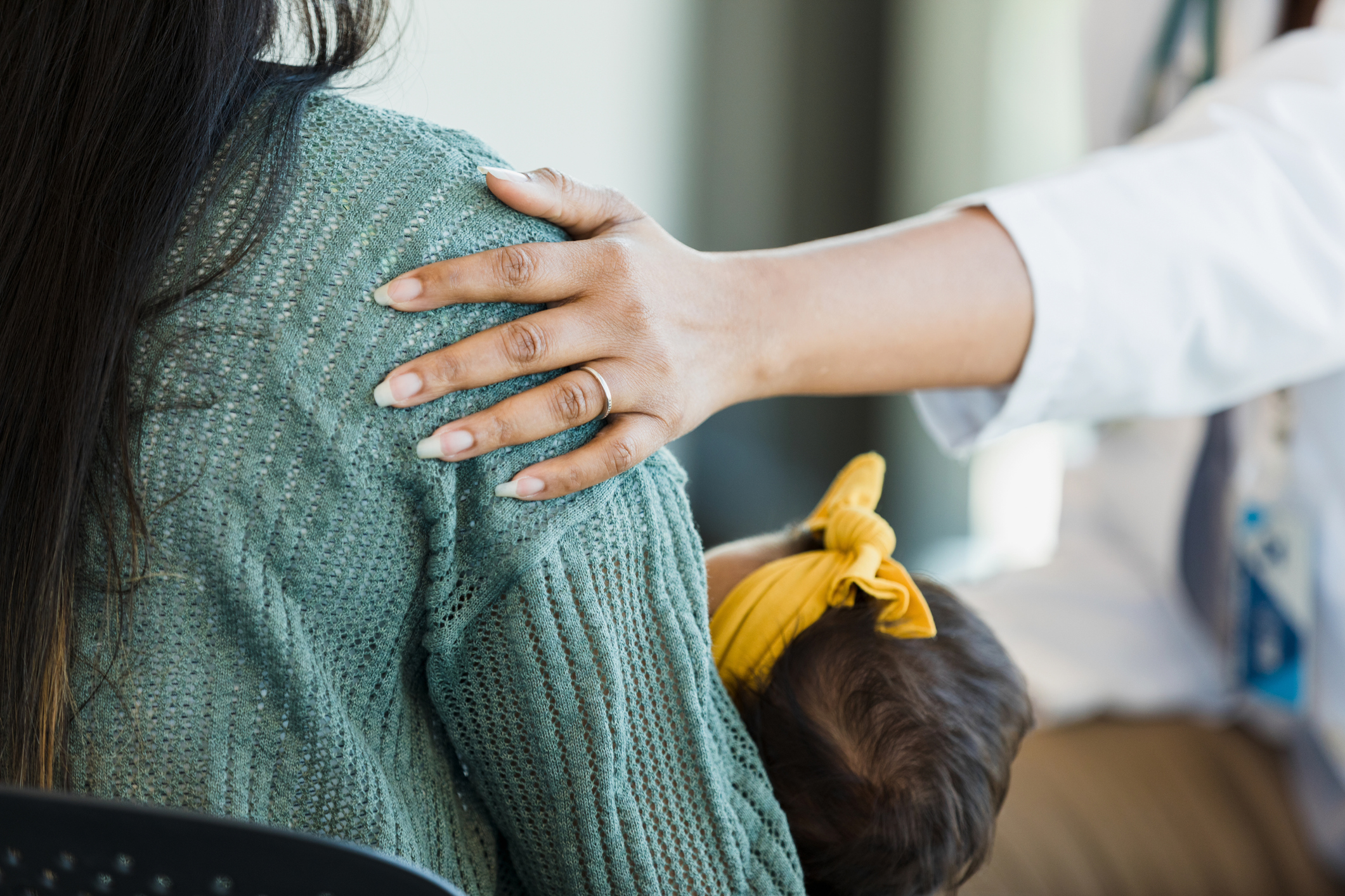 Unrecognizable person touches a mother's shoulder